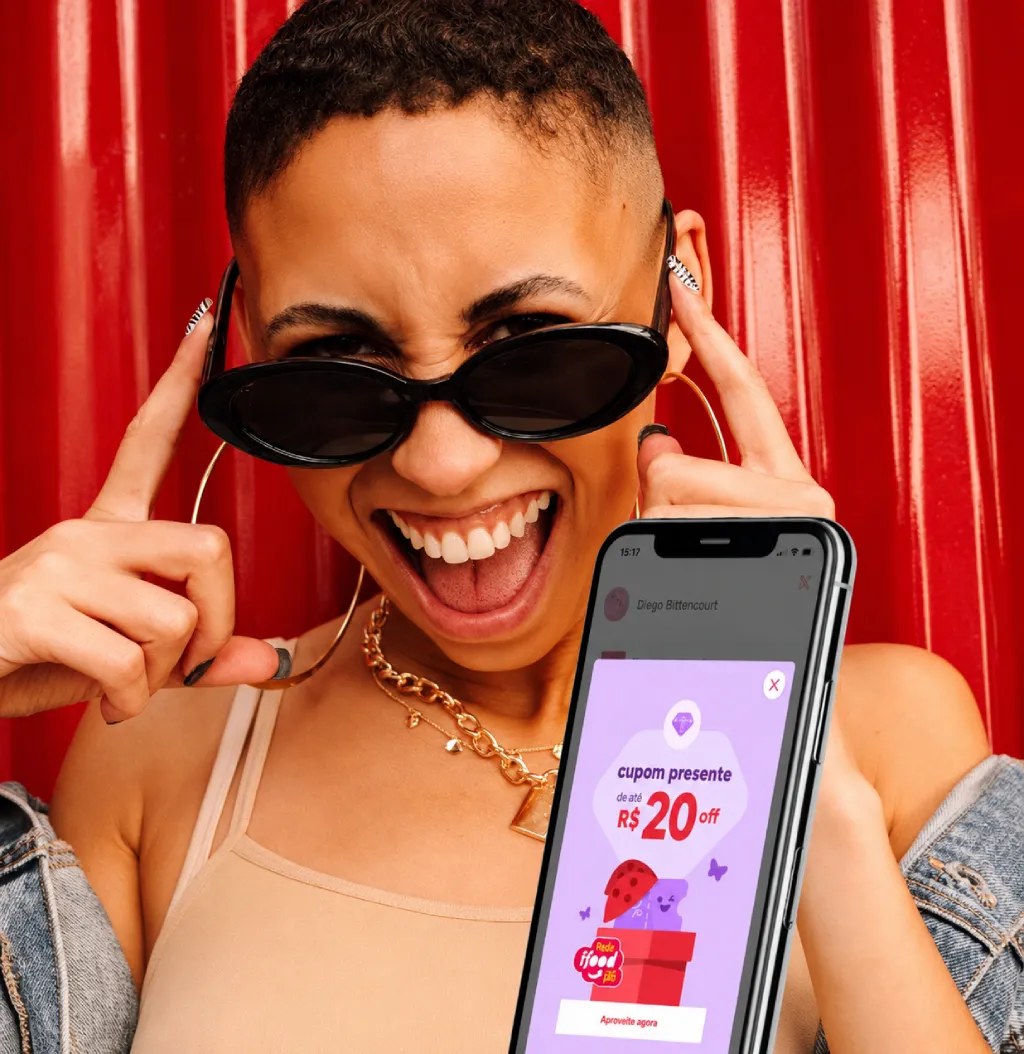 Mulher sorridente segurando um celular com um cupom de desconto do iFood na tela