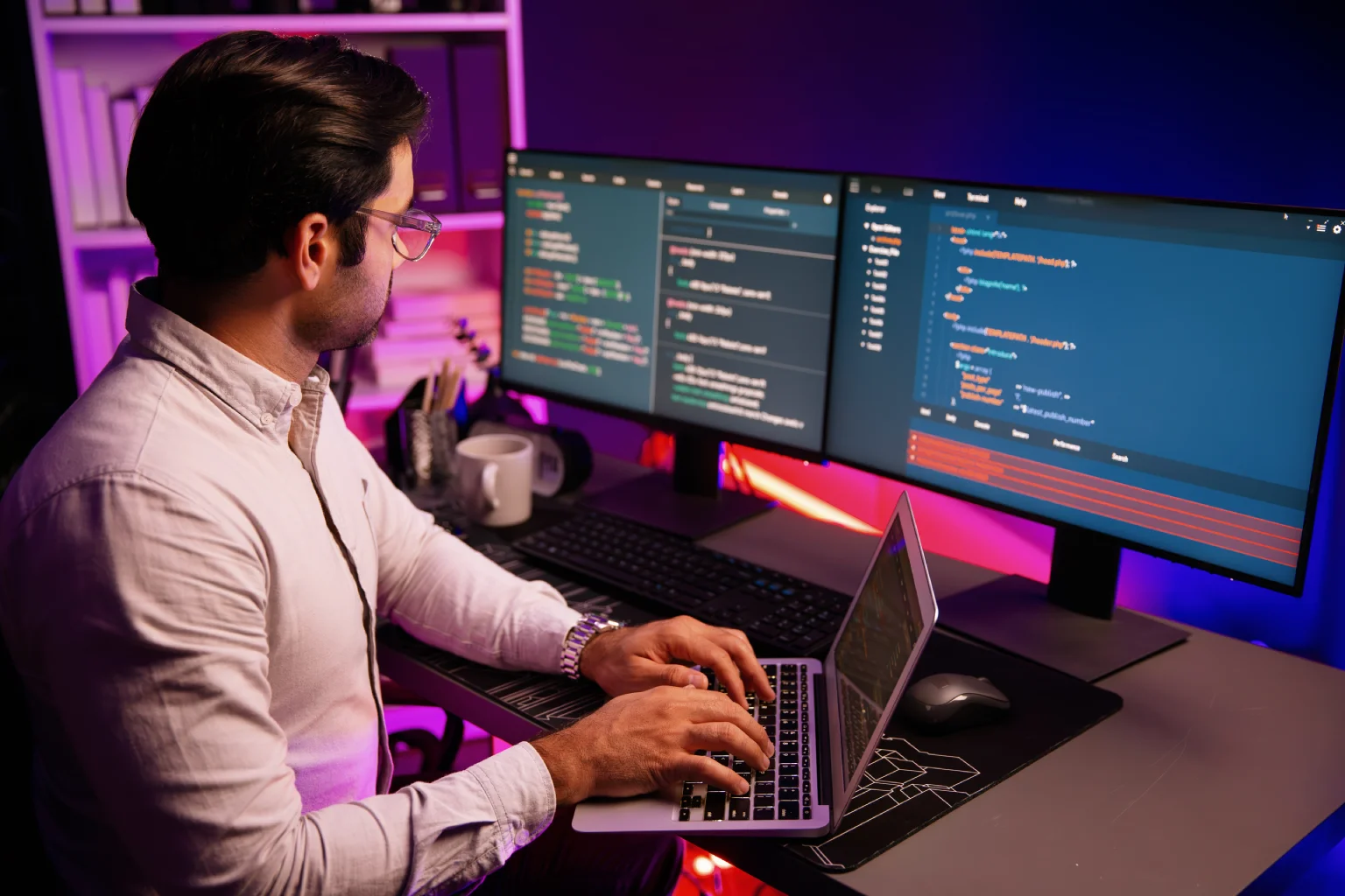 Desenvolvedor trabalhando em múltiplos monitores com código em tela
