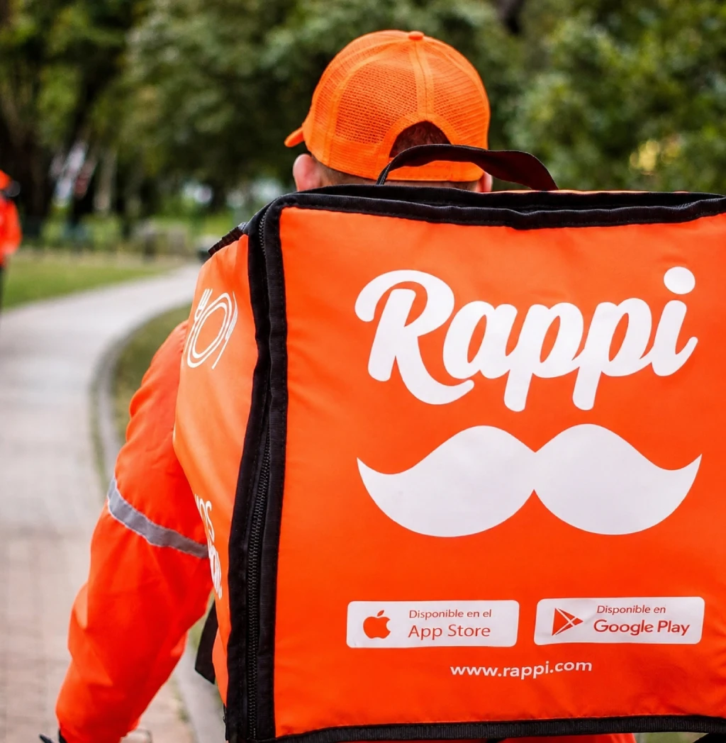 Entregador de bicicleta usando a mochila da Rappi, visto de costas