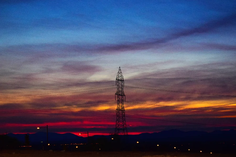 Torre de transmissão de energia ao entardecer, representando o setor de telecomunicações